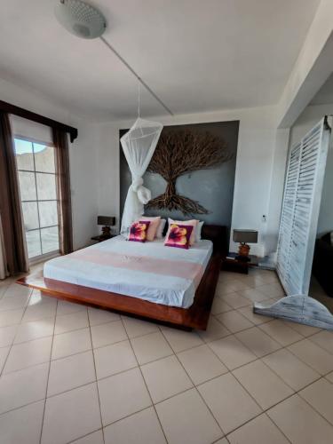 a bedroom with a bed with a tree on the wall at Residence Bethel in Rodrigues Island