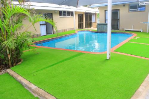 a swimming pool in a yard with green grass at Musina Crown Guest House in Musina