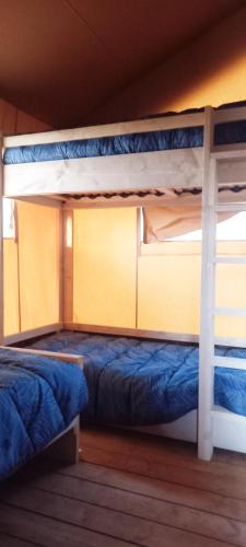 Ce dortoir comprend 2 lits superposés et des draps bleus. dans l'établissement SAFARI LODGE MONPAZIER en pleine nature, à Saint-Cassien