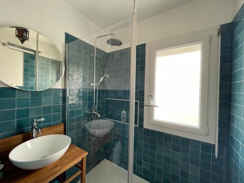 La salle de bains est pourvue de carrelage bleu, d'un lavabo et d'un miroir. dans l'établissement Maison calme à un 15min à pied de la plage, à Royan