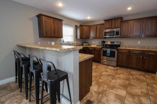 a kitchen with wooden cabinets and a counter with stools at Gateway Retreat 27 miles to Fort Leonard Wood in Saint Robert