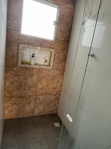 a shower with a glass door and a window at Piscina, Churrasco e Descanso - Santa Clara in Sao Francisco do Itabapoana