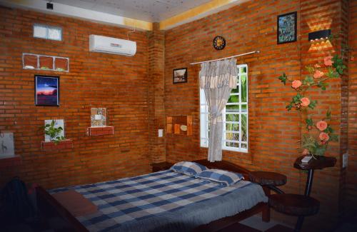 a bedroom with a bed and a brick wall at BOSA Homestay - Mekong Riverside in Can Tho