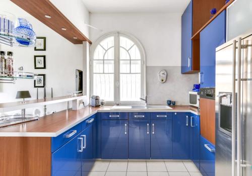 une cuisine avec des placards bleus et une fenêtre dans l'établissement Villa Les Algues, les pieds dans l'eau sur la plage de Rènecros, à Bandol