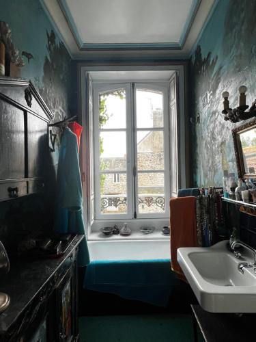 une salle de bain avec un lavabo et une fenêtre dans l'établissement Le Jardin secret du Dr Papertian, à Saint-Clair-sur-lʼElle