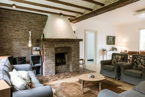 a living room with couches and a brick fireplace at Villa Aluma in Sint-Truiden