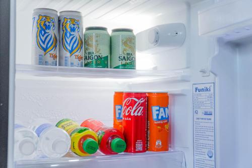 an open refrigerator filled with soda cans and drinks at Amigo Stay Noi Bai Airport in Sóc Sơn