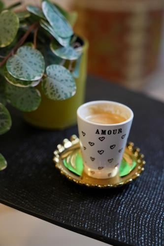 a cup of coffee on a table next to a plant at Dijon Hypercentre - Loge Pompon in Dijon