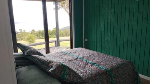 a bedroom with a bed with a blanket and a window at Cabañas Chillwe in Coñao