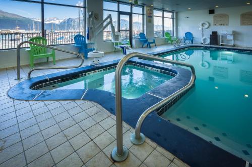 a swimming pool in a hotel with chairs and tables at Harbor 360 Hotel Seward in Seward