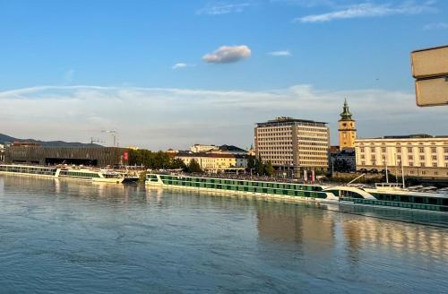 a view of a city with a river and buildings at Donau Bliss Linz City Suite in Linz