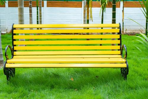a yellow park bench sitting in the grass at Galaxy Garden Resort in Kallār