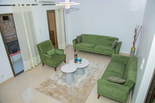 a living room with two green chairs and a table at Résidence FARASELAA in Dakar