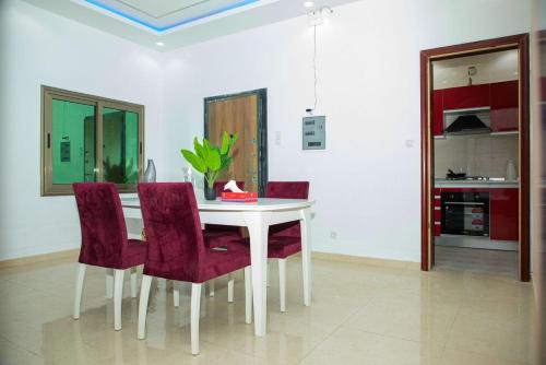 a dining room with a white table and purple chairs at Résidence FARASELAA in Dakar