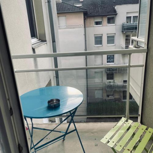 une table bleue sur un balcon avec vue sur un bâtiment dans l'établissement Studio proche Strasbourg, à Schiltigheim