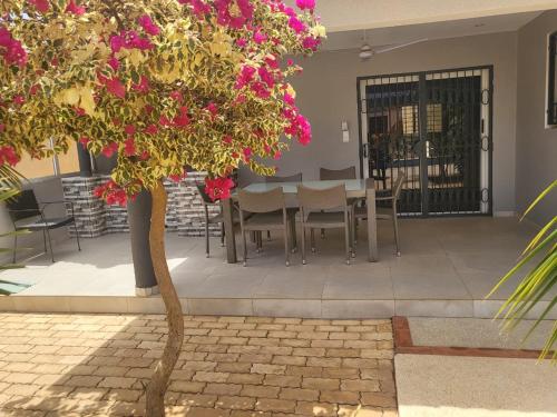 a table and chairs and a tree with pink flowers at Villa luxueuse à ngaparou saly center in Ngaparou