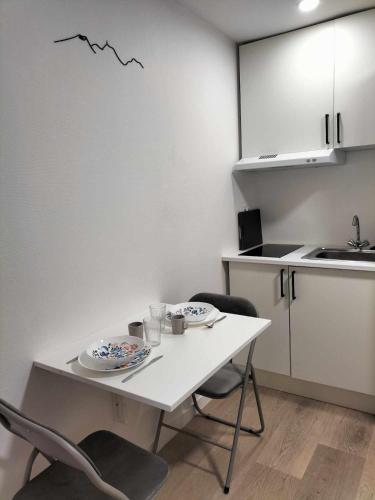 une cuisine avec une table, deux chaises et un comptoir dans l'établissement Appartement calme hypercentre, à Clermont-Ferrand