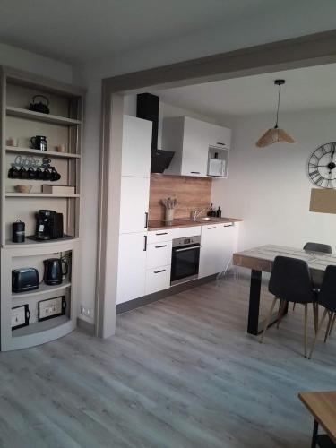 une cuisine avec des armoires blanches et une table dans une pièce dans l'établissement Gite Villa Turckheim, à Turckheim