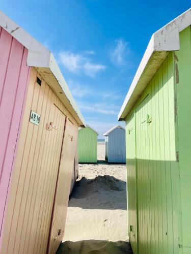une rangée de cabanes de plage colorées sur une plage dans l'établissement Nid douillet - Balcon - Proximité immédiate de la Plage de Berck, à Berck-sur-Mer