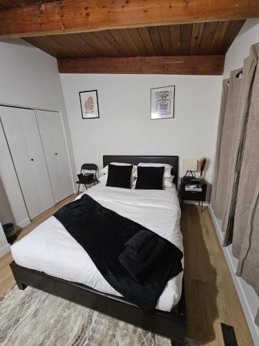a bedroom with a bed with white sheets and black pillows at P&N Suites - Queen Room- DUBAI in Edmonton