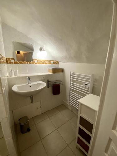 une salle de bain blanche avec un lavabo et un miroir dans l'établissement Gîte Barésia, à Les Brousses