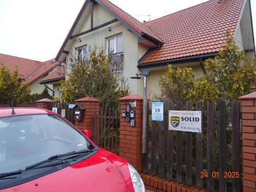 a red car parked in front of a house with a sold sign at Wynajem pokoi Białystok in Białystok