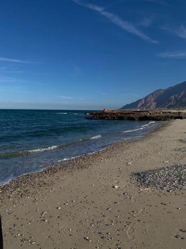 a beach with a rocky shore and the ocean at Sifah seaCottage in Muscat