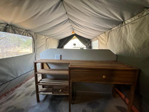 a bed and a desk in a tent at Omulunga Bush Camp in Ruacana
