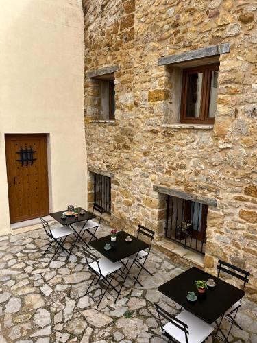 two tables and chairs in front of a stone building at CASA RURAL MASIA ARINESA Culla in Culla