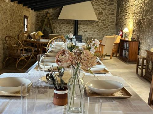 a table with plates and flowers in a room at CASA RURAL MASIA ARINESA Culla in Culla