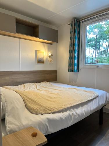 une chambre avec un grand lit avec une fenêtre dans l'établissement On est trop bien ici, à Lège-Cap-Ferret