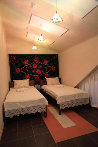 two beds in a room with a painting on the wall at ECO Hotel Gagauz Sofrasi in Congaz