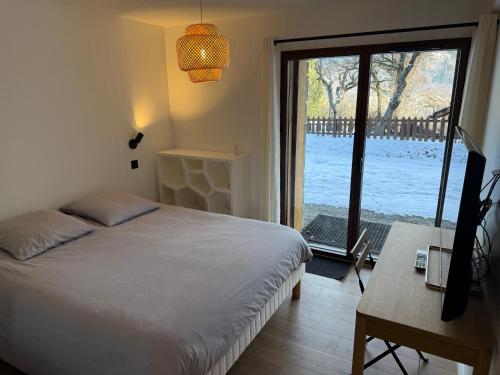 une chambre avec un lit et une porte coulissante en verre dans l'établissement Chalet Chaumière, à Les Allues