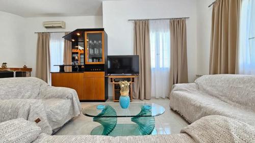 a living room with a couch and a glass table at SUNSET VILLA MILOS pera triovasalos in Triovasálos