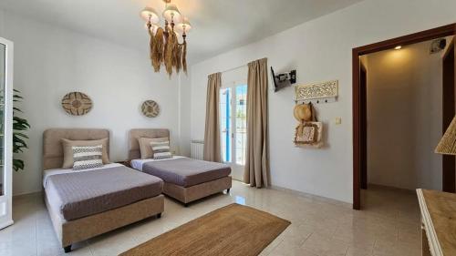 a room with two beds and a couch and a chandelier at SUNSET VILLA MILOS pera triovasalos in Triovasálos