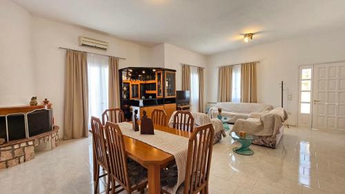 a living room with a table and chairs and a couch at SUNSET VILLA MILOS pera triovasalos in Triovasálos