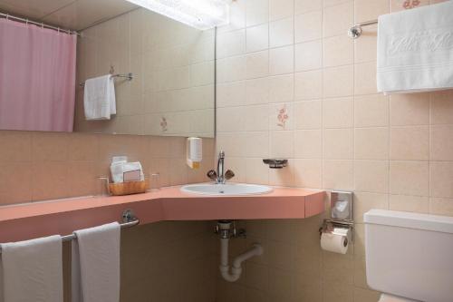 a bathroom with a sink and a mirror and a toilet at Seiler au Lac in Bönigen
