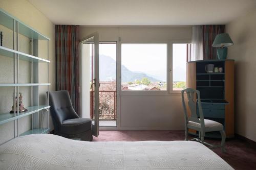 a bedroom with a bed and a chair and a window at Seiler au Lac in Bönigen