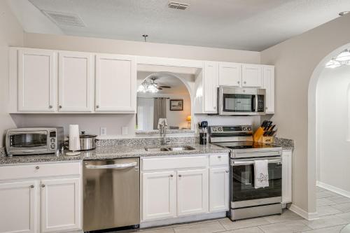 a kitchen with white cabinets and stainless steel appliances at 8 Mi to Legoland Winter Haven Home with Lanai! in Winter Haven