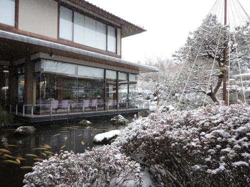 a house covered in snow next to a pond at Yoshimatsu in Hakone