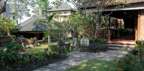 a garden in front of a house with a sign at Murni's Houses & Spa in Ubud