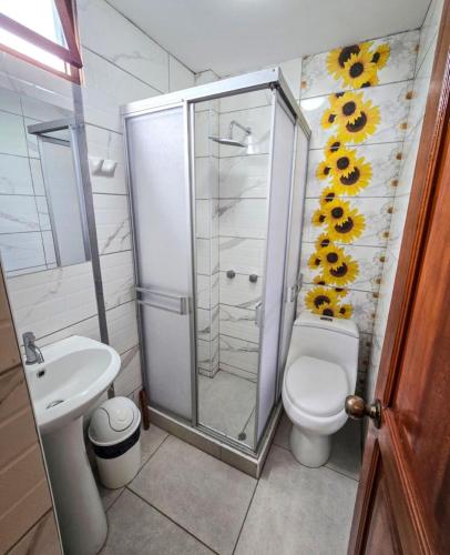 a bathroom with a toilet and a shower with sunflowers on the wall at Hospedaje Wendy in Puerto Chicama