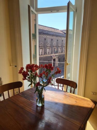 een vaas met bloemen op een houten tafel met een raam bij Art house Venusio luxury home in Napels