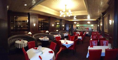 a restaurant with white tables and red chairs at Gilmore Hotel, Trademark Collection by Wyndham in Ketchikan