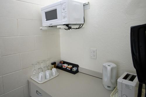 a bathroom with a microwave on the wall and a sink at Midway Pacifica Lodge in Lower Hutt