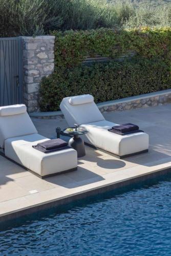 two lounge chairs sitting next to a swimming pool at OD Luxury Villa in Pylos