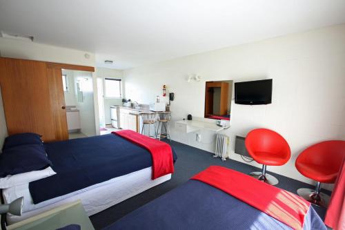 a bedroom with a bed and a desk and a television at Midway Pacifica Lodge in Lower Hutt