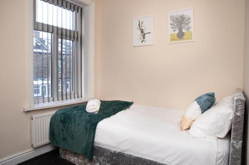 una cama en una habitación con ventana en Woodhall Avenue, en Bradford