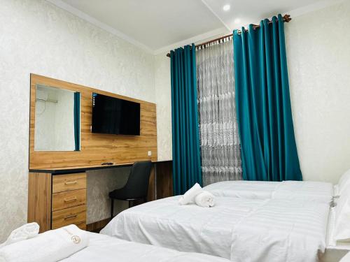 a hotel room with two beds and a television at Soro Hotel in Dushanbe