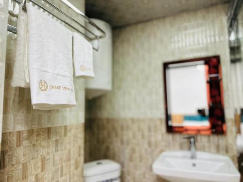 a bathroom with a sink and a toilet and towels at Soro Hotel in Dushanbe